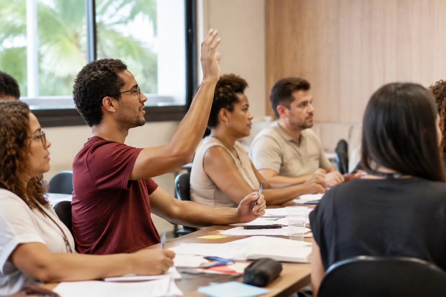 Estudante levantando a mão em uma mesa de seminário coberta de anotações
