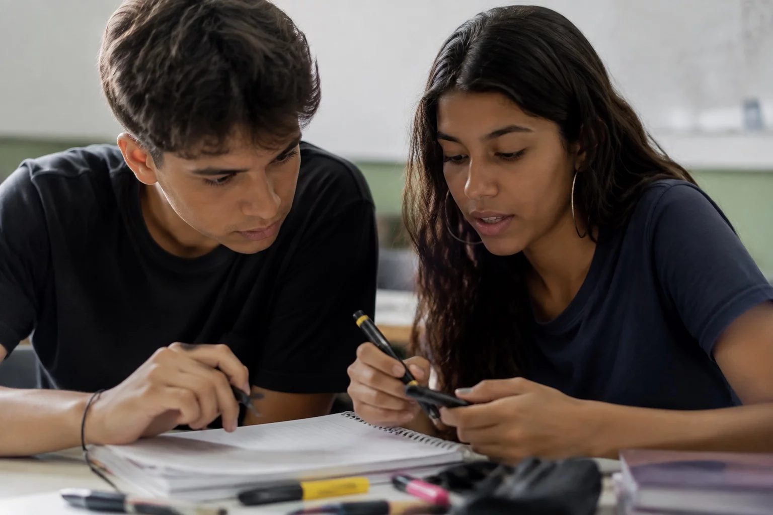 Dois estudantes preparando um debate com cadernos e marcadores